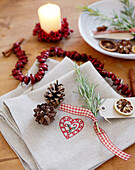 Pine cones and rosemary at Christmas place setting with beaded rosehips