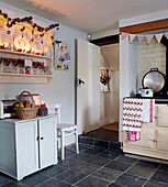 Lit candles on kitchen dresser in country kitchen with tea towels on Aga