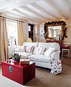 White two seater sofa and red chest in reception room with fairy lights and garland over gilt framed mirror