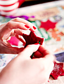 Woman making red star-shaped Christmas decorations