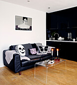 Black fitted kitchen with leather sofa and candles on Perspex table
