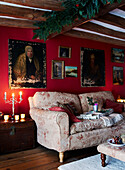 Artwork and sofa with lit candles under beamed ceiling of country home