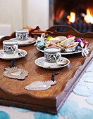 Coffee cups and mince pies on wooden tray at fireside