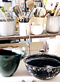 Paint brushes and craft tools on workbench with black plastic bowl