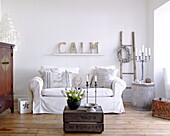 Weißer Schonbezug auf Sofa unter Schriftzug 'CALM' im Wohnzimmer eines Hauses in City of Bath Somerset, England, UK