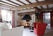Open fire in exposed stone fireplace living room in renovated Cotswolds mill house England UK