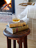 Whisky glass and books on carved side table in living room of Hampshire home England UK