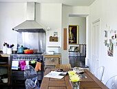 Backofen und Dunstabzugshaube aus rostfreiem Stahl mit bunten Auflaufformen und Geschirrtüchern in der Küche eines Londoner Familienhauses UK