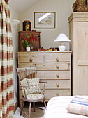 Chest of drawers in pale wood with chair and cushions in Hexham country house Northumberland England UK