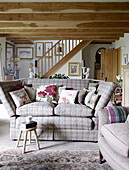 Checked sofa with floral cushions in open plan beamed interior of Hexham country house Northumberland England UK