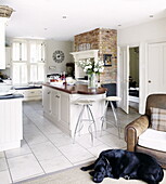 Sleeping dog in open plan kitchen with shuttered windows and breakfast bar in Guildford home Surrey England UK