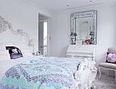 Turquoise quilted cover on white carved antique bed in London home UK