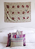 Floral wall hanging above bed with tapestry pillows London UK