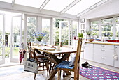 Kitchen table in conservatory extension opening onto back garden of London home UK