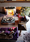 Elevated view of Christmas tree and purple sofa at lit fire in festive Oxfordshire home, England, UK