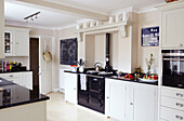Cremefarbene und schwarze Küche mit Aga und Kreidetafel in einem Haus in Warwickshire, England, Vereinigtes Königreich