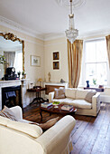 Two seater sofas at fireside in drawing room with wooden floor in Warwickshire home, England, UK