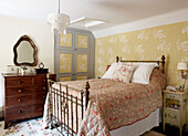 Floral wallpaper and quilt with brass bed in Oxfordshire farmhouse, England, UK