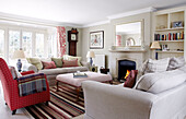 Armchair and sofas with lit fire in Oxfordshire home, England, UK