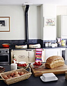 Eggs and bread with tomatoes in Oxfordshire farmhouse kitchen with black splashback and cream Aga, England, UK