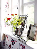 Framed pictures and cut flowers on windowsill of Oxfordshire home, England, UK