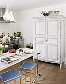 Retro bar stools at kitchen table with painted dresser in Oxfordshire cottage, England, UK