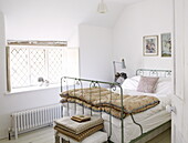 Metal framed bed with quilt and leaded window in bedroom of Oxfordshire cottage, England, UK