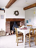 Bread on table with pew chairs in cottage with beamed ceiling and brick fireplace in Staffordshire home, England, UK