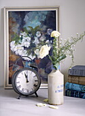 Cut flowers and alarm clock with artwork and books in Woodstock home, Oxfordshire, England, UK
