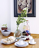Single stem flower with focaccia bread, fruit and coffee cups in Little London home, Guildford, Surrey, UK