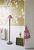 Standard lamp behind door of living room with blossom patterned wallpaper in contemporary apartment, Amsterdam, Netherlands
