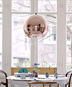 Chairs at table below copper pendant light in contemporary apartment, Amsterdam, Netherlands