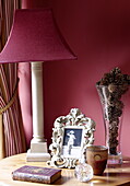 Red lamp and pinecones in vase with vintage photograph on wooden side table, Oxfordshire, England, UK