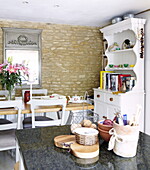 Open plan kitchen with exposed stone wall and painted kitchen dresser in Oxfordshire, England, UK
