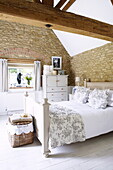 Doppelbett in einem Schlafzimmer in einer umgebauten Scheune aus Naturstein, Oxfordshire, England, UK
