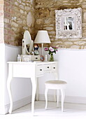 White dressing table and stool with carved and oval mirrors in bedroom of barn conversion, Oxfordshire, England, UK
