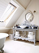 Wash basin and oval shaped mirror in attic bathroom of barn conversion, Oxfordshire, England, UK