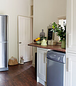 Upright fridge and dishwasher in kitchen with door held open with doorstop in North London home, England, UK