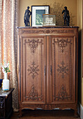 Carved wooden wardrobe with figurines in bedroom of London townhouse England UK