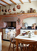Exposed brick fireplace with copper pans in Derbyshire farmhouse kitchen England UK