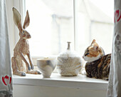Glasiertes Keramikkaninchen und Katze auf der Fensterbank eines Bauernhauses in Derbyshire England UK
