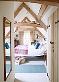 Blick durch die Tür zum Schlafzimmer mit Balken im Dachgeschoss einer umgebauten Scheune in Nottinghamshire England UK