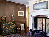 Painted cabinet dated 1860 with embroidered firescreen and brick fireplace in traditional country house Welsh borders UK