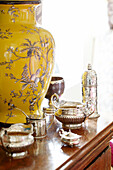 Silverware with oriental lamp base on wooden sideboard in Oxfordshire country house England UK