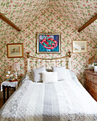 Floral patterned wallpaper in attic bedroom of Oxfordshire country house England UK