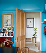 Drinks cabinet below portrait of Queen in dining room with wooden doorway to hall in Auckland home North Island New Zealand