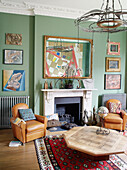 Pair of armchairs with artwork collection above fireplace in Notting Hill home West London UK
