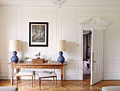 Stools at wooden table with blue matching lamp bases in panelled Bicester drawing room Oxfordshire England