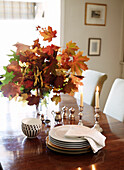 Autumn leaves and lit candles on Bicester dining table Oxfordshire England