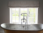 Shower fitting on freestanding metallic bath at window of Buckinghamshire home UK